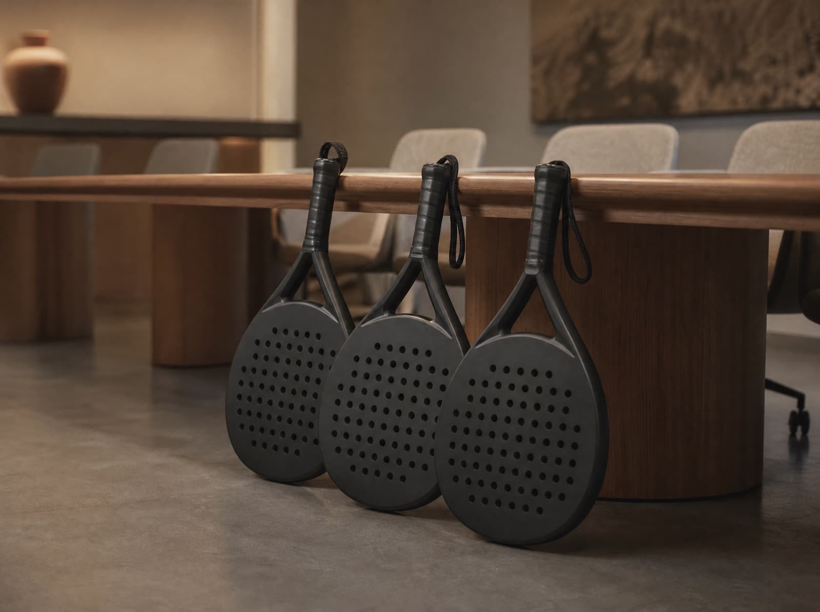 Drie custom padel rackets naast elkaar tegen een vergadertafel
