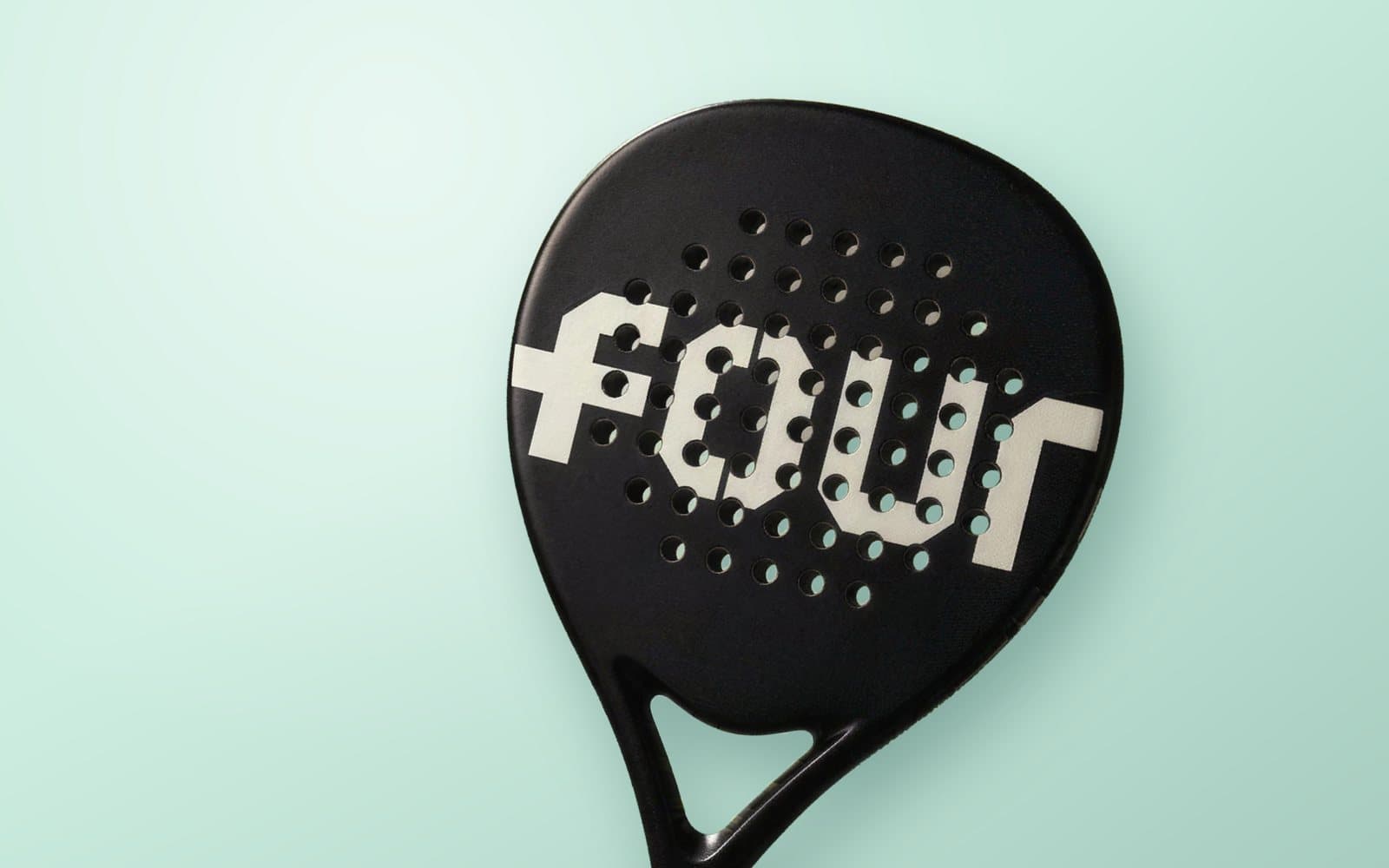 Zwart custom padel racket met het witte woordmerk FOUR op het slagvlak, op een mintgroene achtergrond